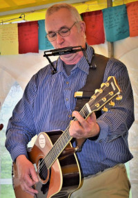 Steve Robert playing guitar and harmonica